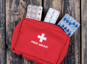 red medical kit with white plus sign and several pill packages sticking out of the top